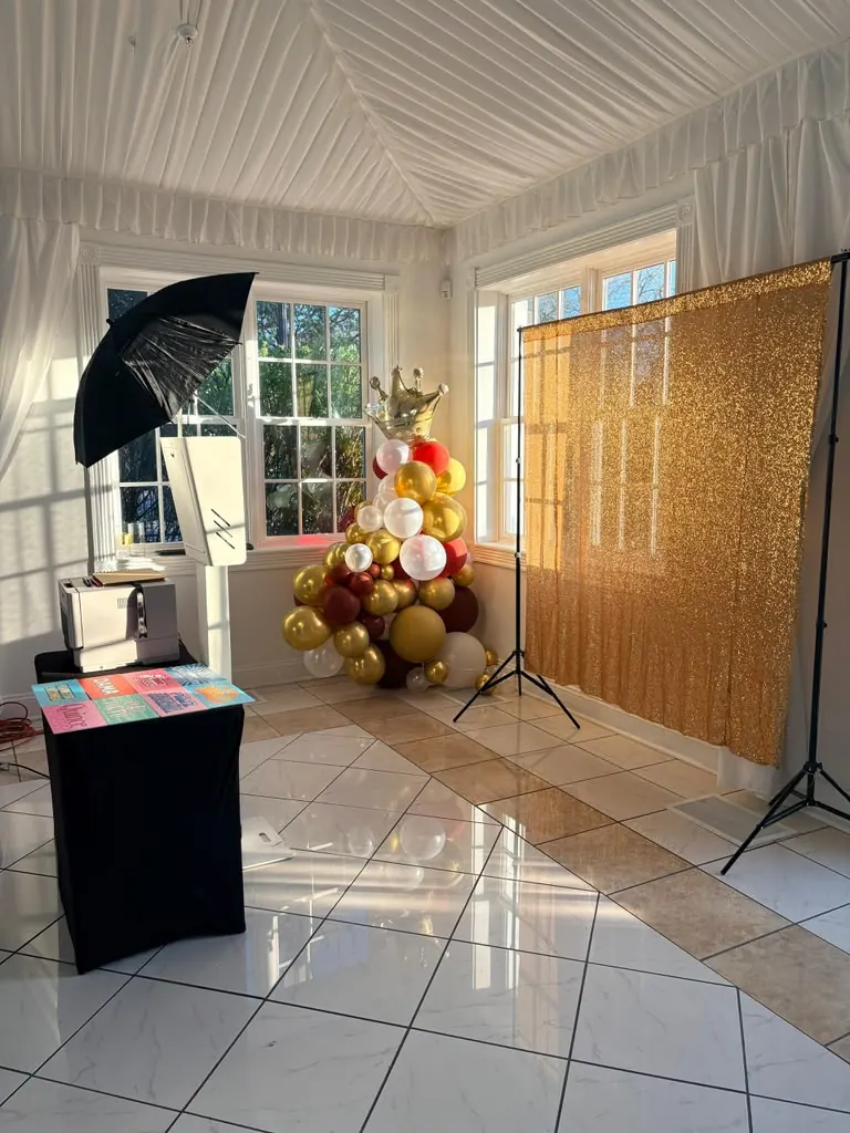 Photo booth with a gold sequin backdrop and balloon column