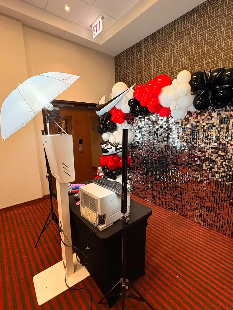 Printer photo booth with a silver sequin wall and balloon garland