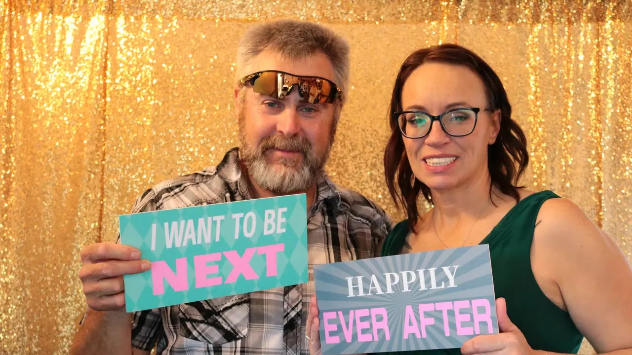 Couple holding happily ever after signs at a photo booth