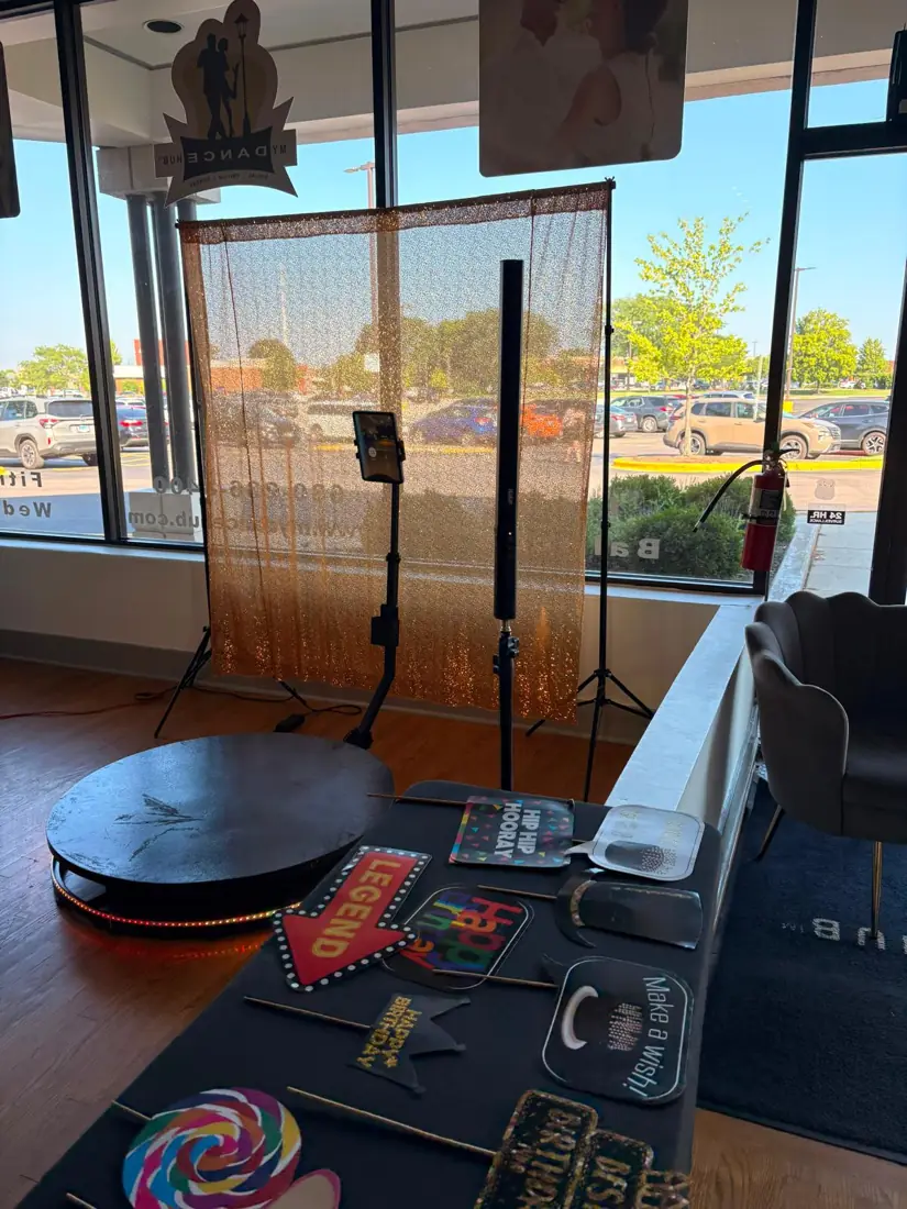 Tablet photo booth on a stand with a gold sequin backdrop and a table of props