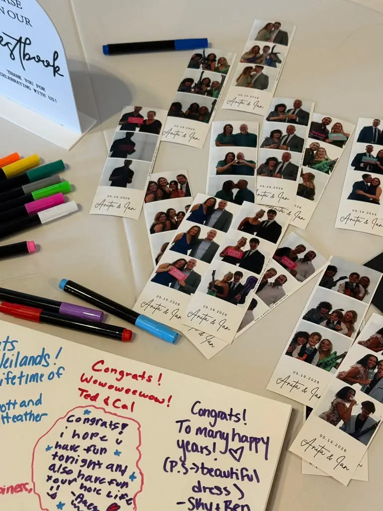 Photo strips spread on a guestbook table with colorful markers